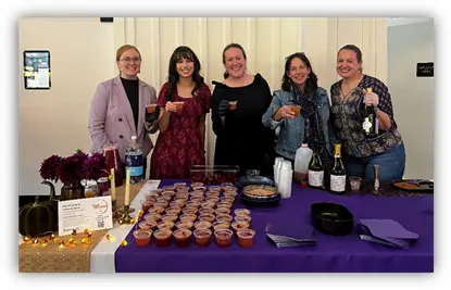 Five people smiling behind CANDLE’s station at the gala.