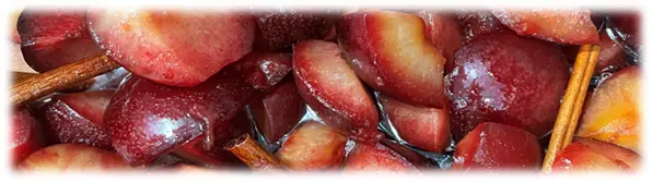 Plum slices simmering in syrup with cinnamon sticks.