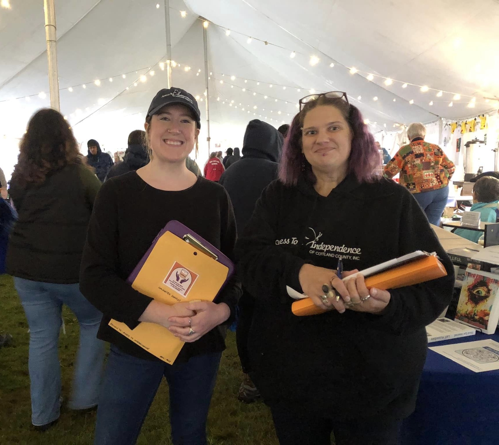 Two white women are holding CANDLE surveys and smiling at the camera.